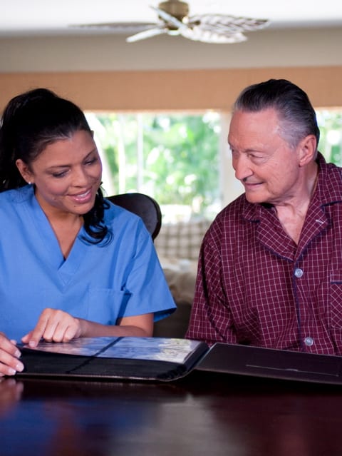 Nurse and senior man flipping through a photo album | Credit: ARARF